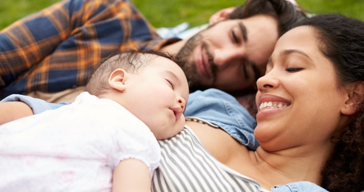 New parents lay in the park with their infant