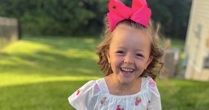 A smiling young girl wearing a big red bow in her hair