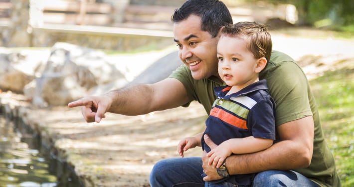 A Latino father at the park with his young son
