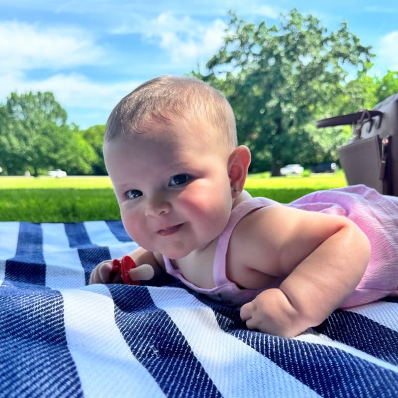 A baby on a blanket at the park